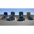 Completed multi-tank installation site with four powder-coated tanks on concrete pads with containment pans and pump platforms